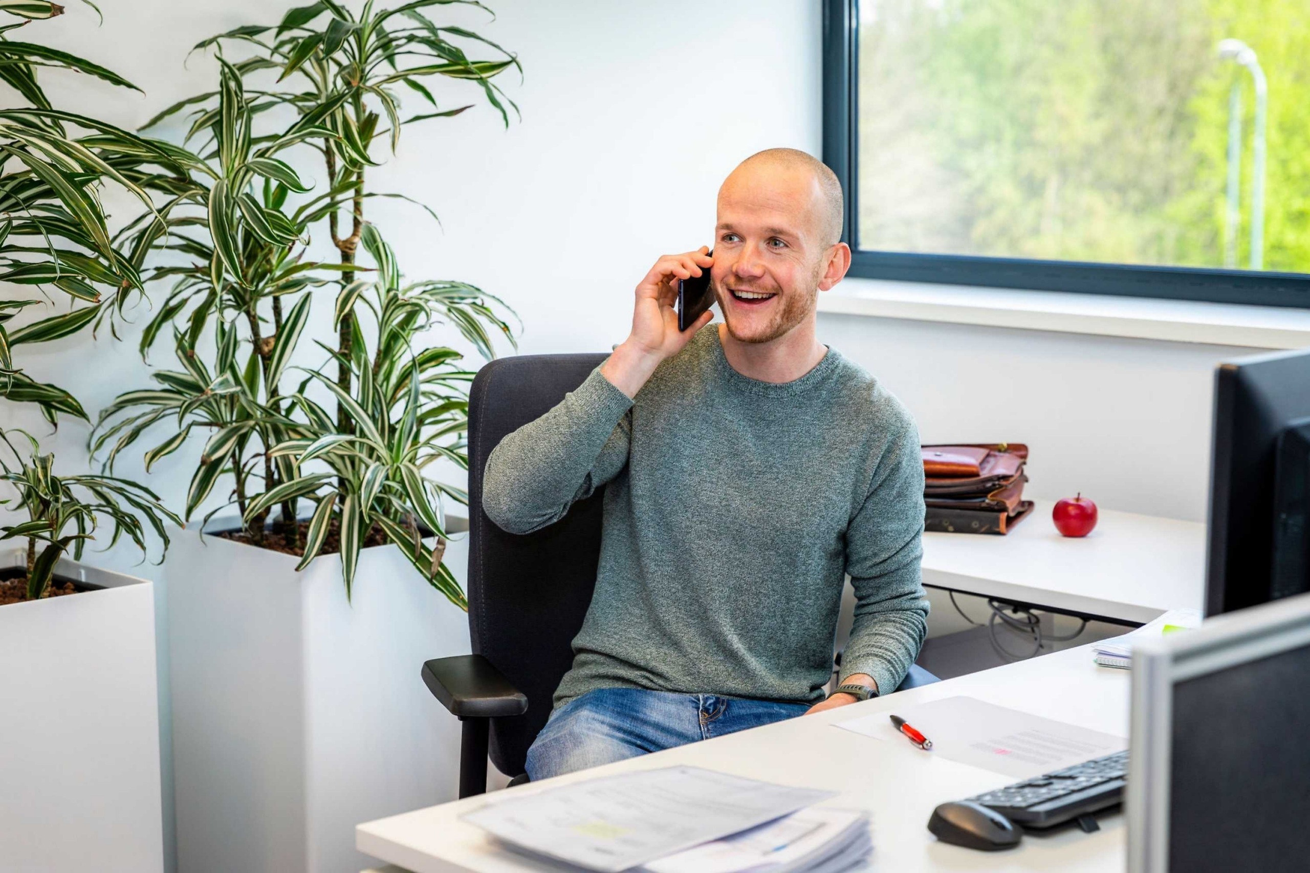 Medewerker van Faes voert een telefoongesprek aan zijn bureau, passend bij advies over het berekenen van de totale kosten van industriële verpakkingen.