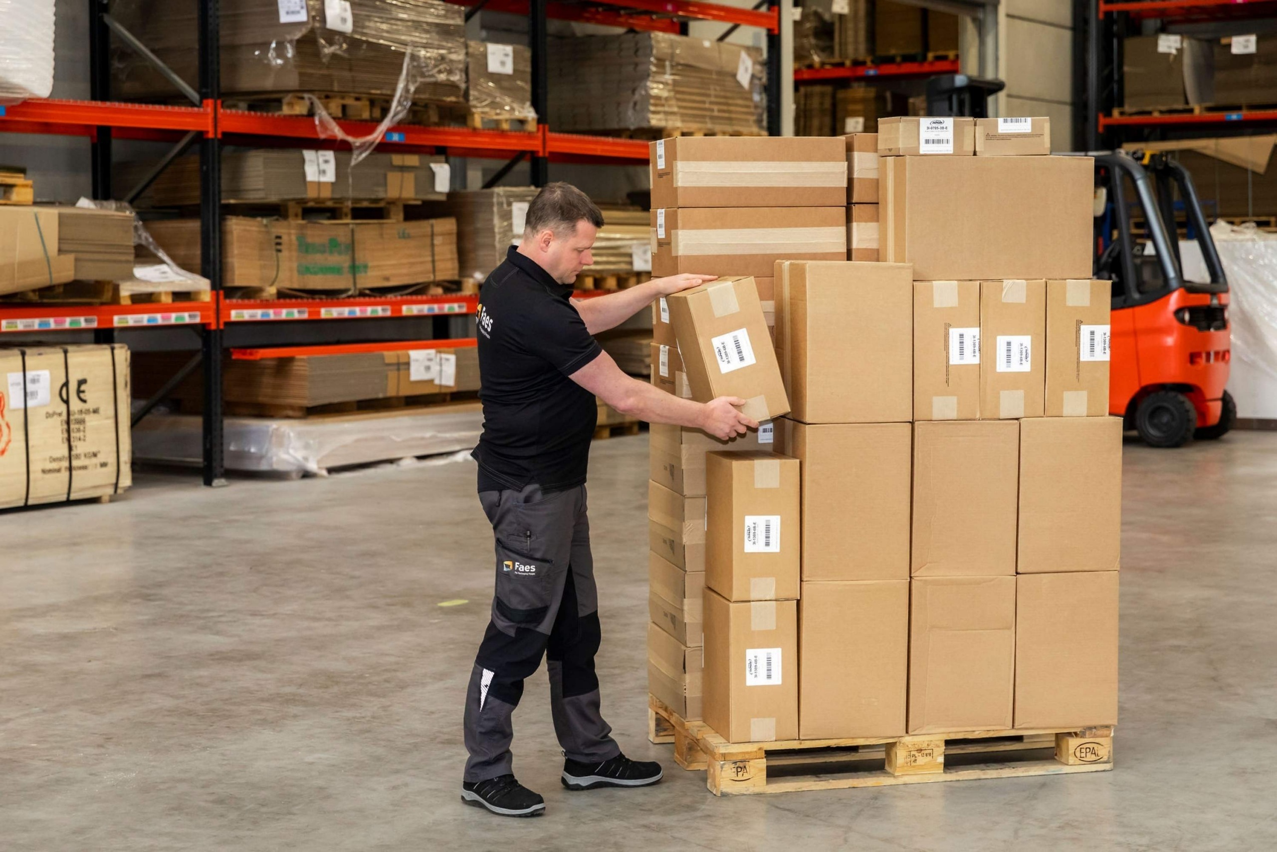 Medewerker van Faes stapelt en controleert dozen op een pallet in het magazijn, passend bij het belang van goede transportverpakking om DOA-schade te helpen beperken.