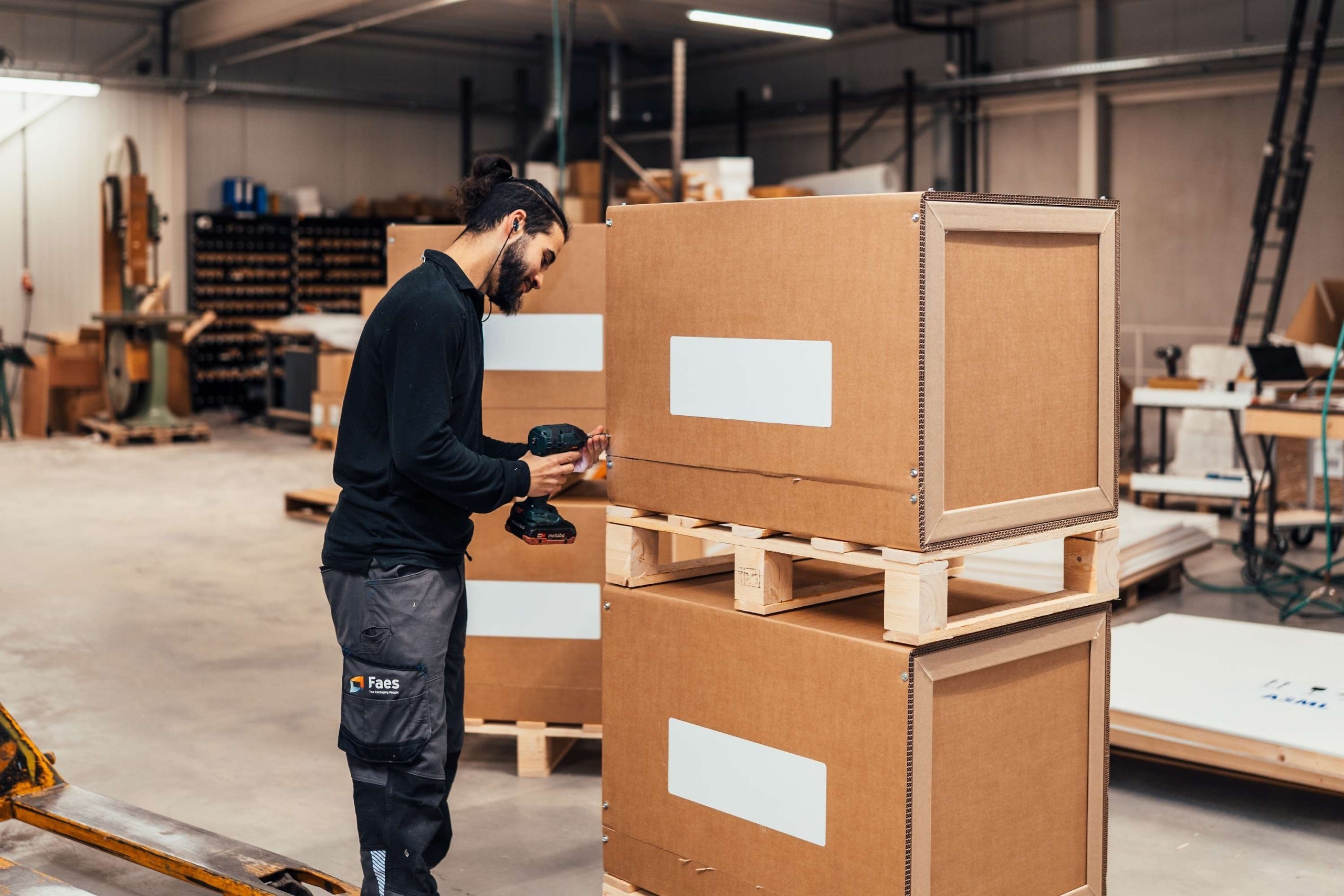 Faes medewerker assembleert een grote kartonnen maatwerkverpakking, passend bij het meenemen van duurzaamheidskosten in de total cost of ownership van industriële verpakkingen.