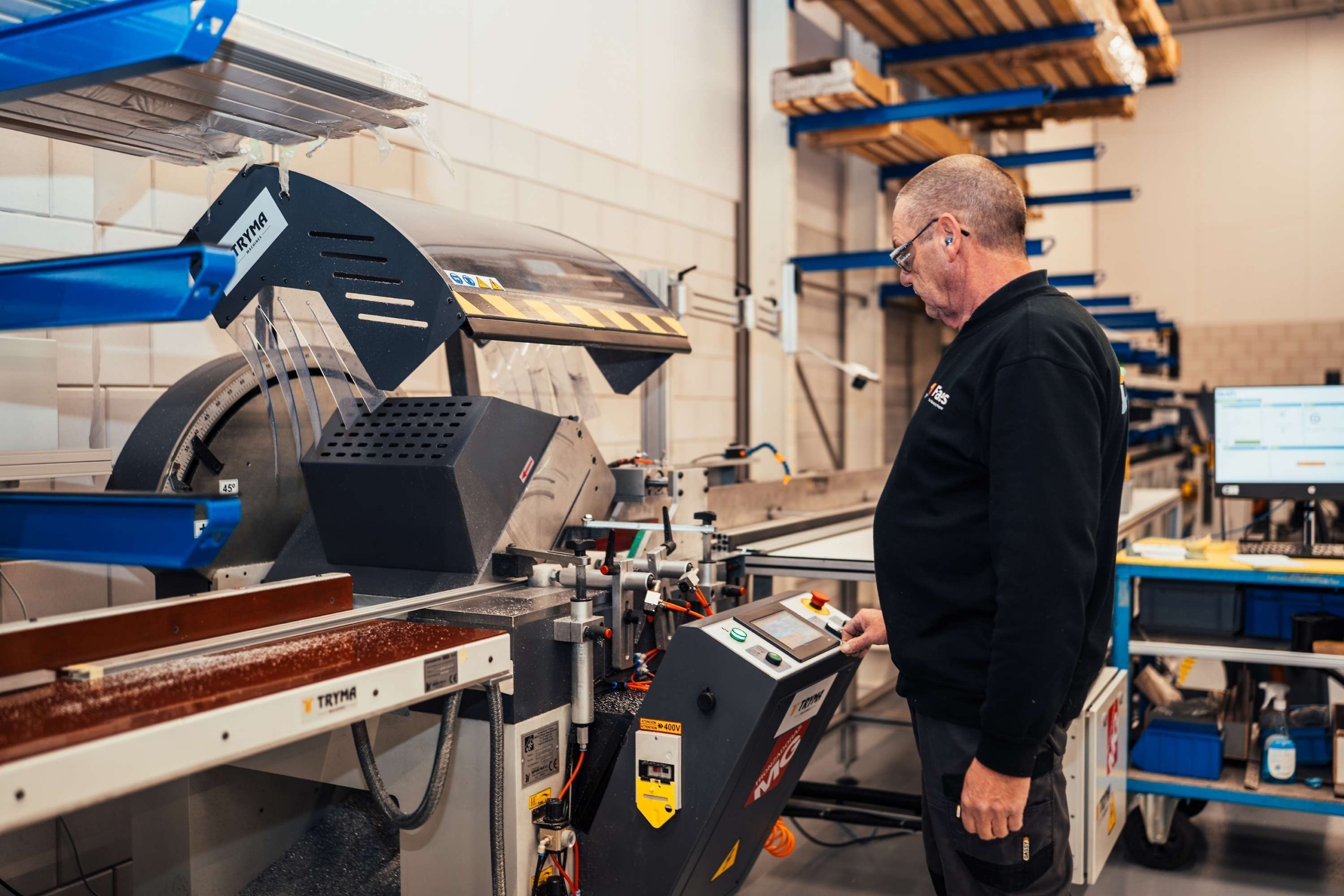Medewerker van Faes bedient een machine in de productiehal voor het nauwkeurig verwerken van profielen, waarbij efficiënt materiaalgebruik bijdraagt aan minder verspilling in de supply chain.