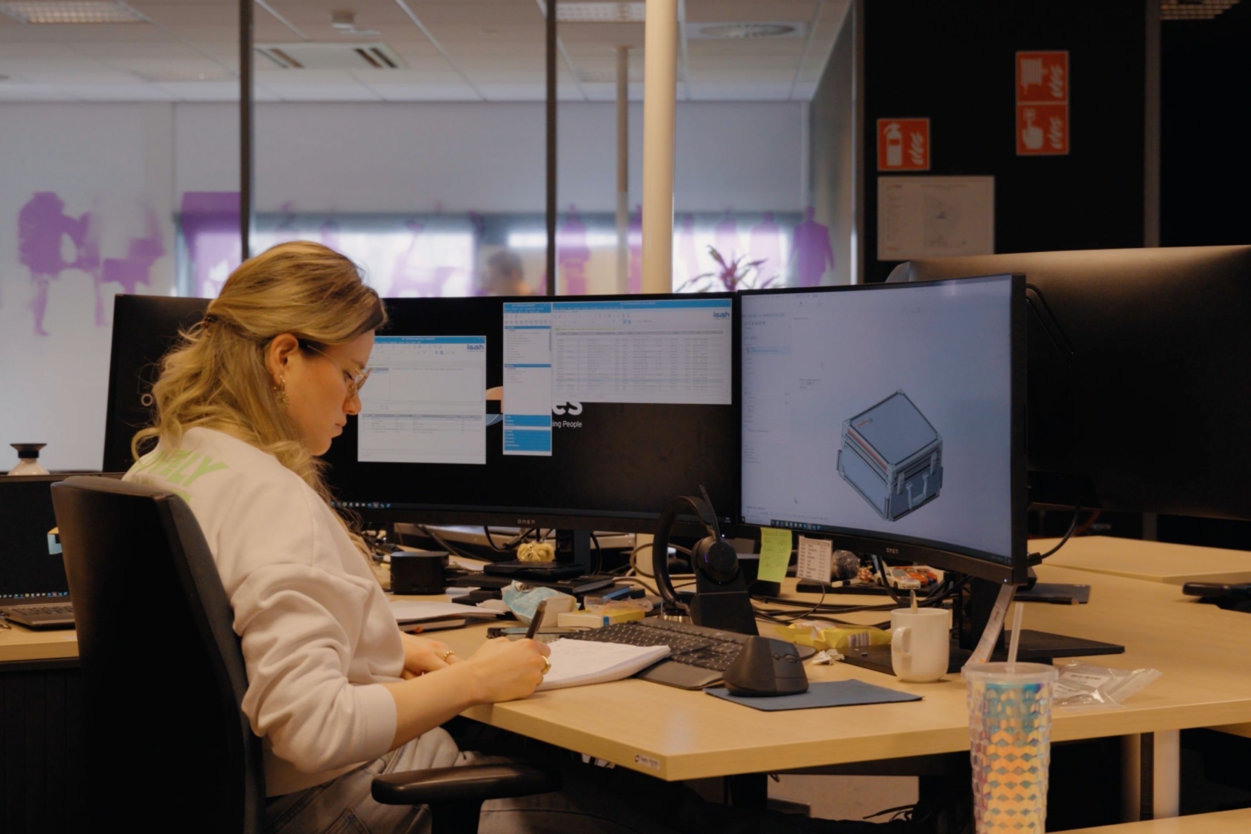 Medewerker van Faes werkt aan een technisch ontwerp van een transportcase op meerdere schermen, passend bij controle en maatwerkverpakkingen in complexe automotive supply chains.