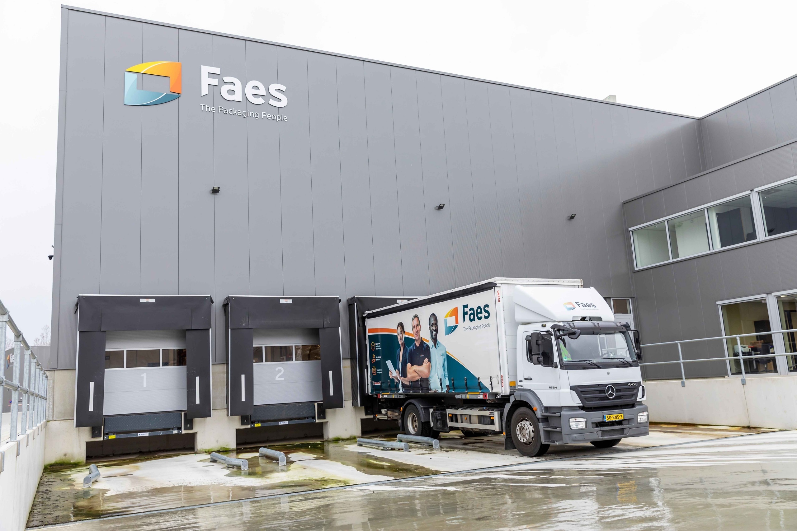 Faes vrachtwagen staat bij het laadperron van het distributiecentrum, passend bij transportprocessen waarbij ADR-regelgeving voor gevaarlijke stoffen belangrijk is.