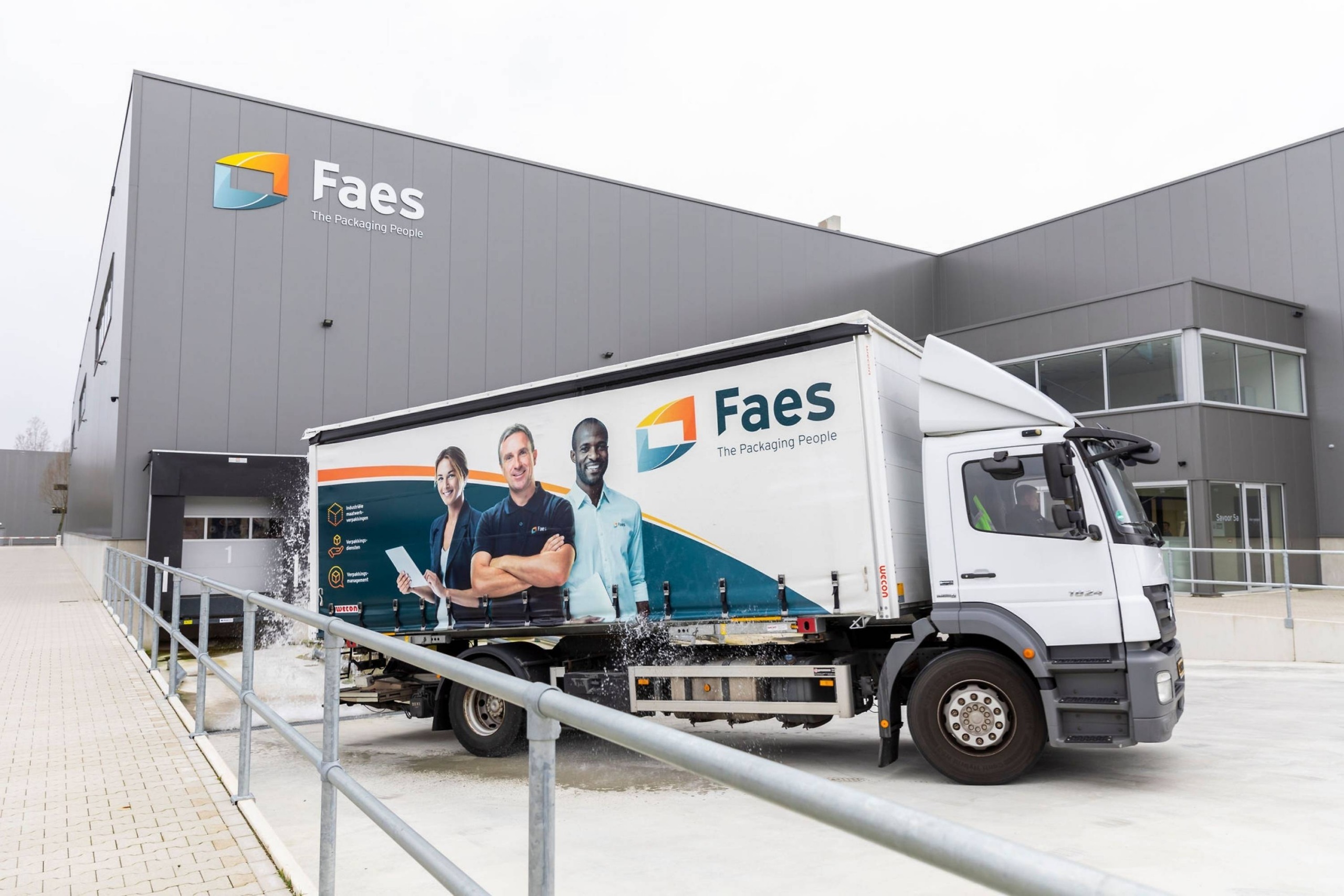 Faes vrachtwagen staat bij het laadperron van het Faes pand, met opspattend water rond de laadzone als herkenbare transportomgeving waarin vochtbeheersing belangrijk kan zijn.