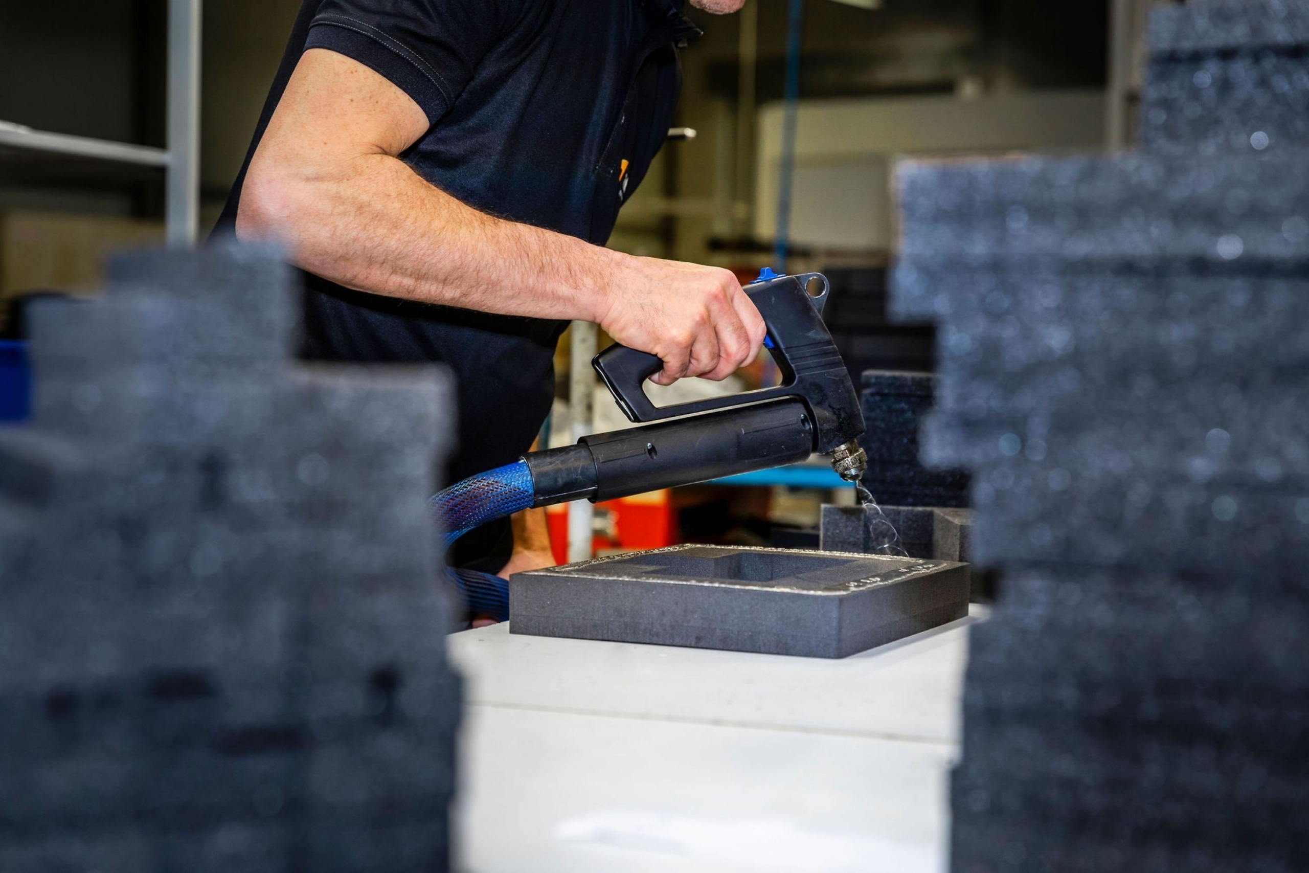 Medewerker van Faes bewerkt een zwart foam-interieur in de productieomgeving, passend bij een artikel over het voorkomen van DOA-problemen bij high-tech componenten tijdens transport.