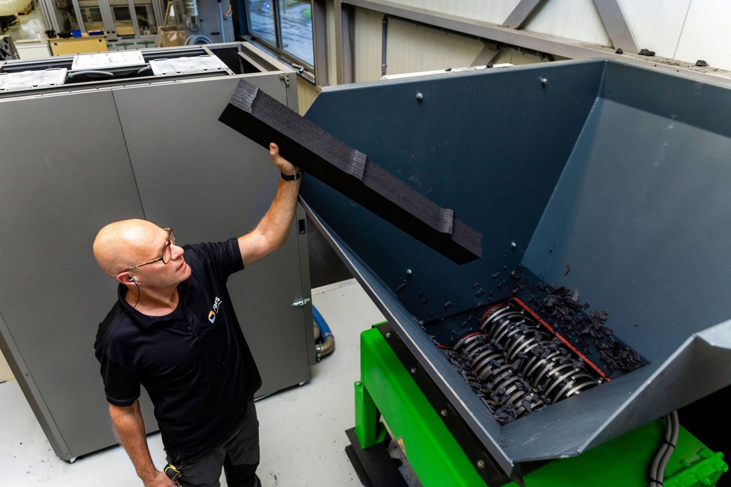 Medewerker van Faes voert een PE-foam onderdeel in een industriële shredder, passend bij het hergebruik van schuimafval binnen circulaire verpakkingsoplossingen.