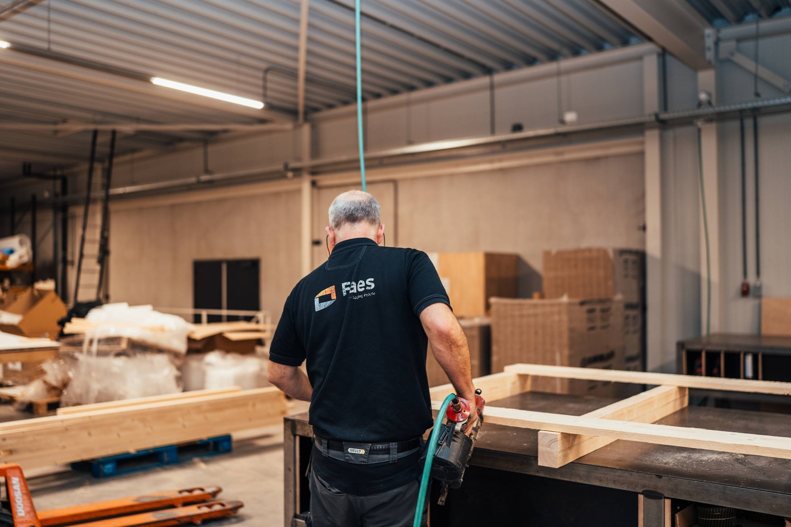 Medewerker van Faes werkt in de productiehal aan een houten transportframe, passend bij het belang van verpakkingskwaliteit voor het beperken van productschade en DOA-risico’s.