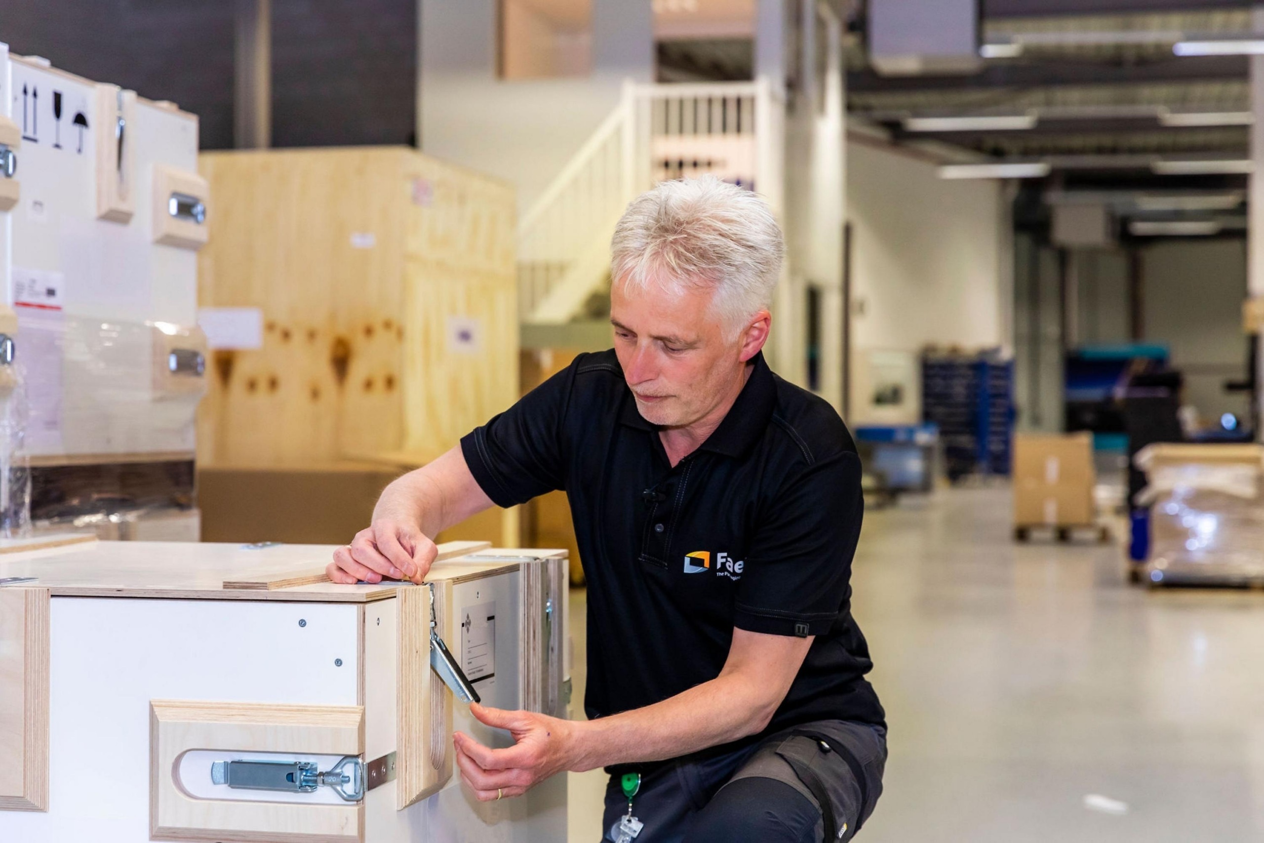 Medewerker van Faes werkt in de productieomgeving aan de sluiting van een stevige transportkist, passend bij een artikel over beschermende tactical cases voor defensie-elektronica.