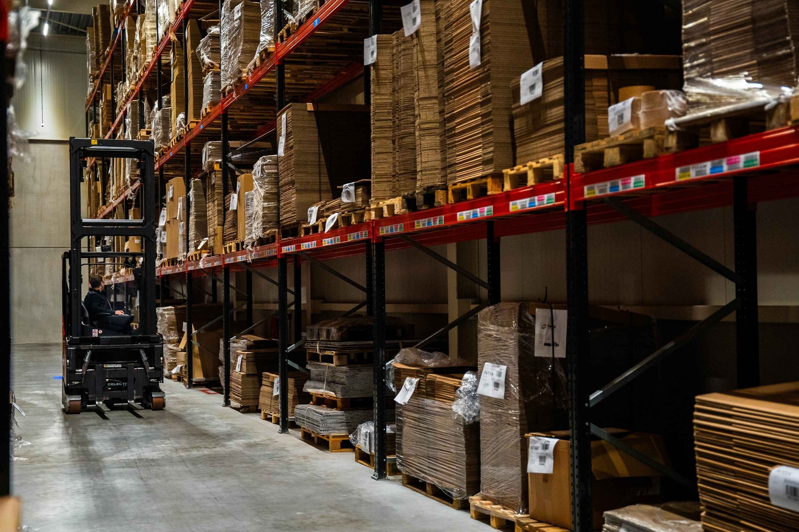 Magazijn van Faes met gestapelde verpakkingsmaterialen en een heftruck, passend bij gecontroleerde opslag en temperatuurbeheersing voor verpakkingen van lithiumbatterijen.