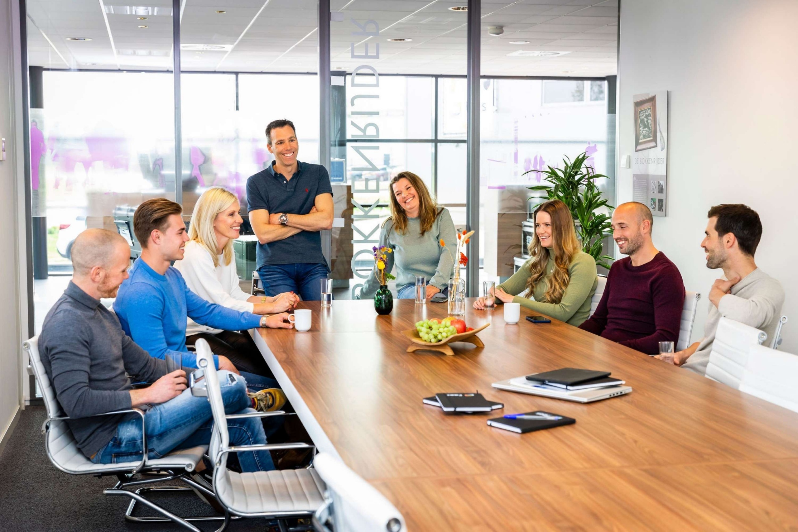 Team van Faes zit in een vergaderruimte rond een houten tafel tijdens een overleg, passend bij een artikel over TCO-analyse en het objectief vergelijken van leveranciers.