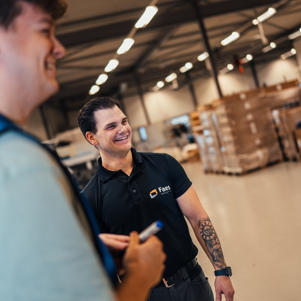 Twee medewerkers van Faes overleggen in de productiehal over kwaliteits- en certificeringseisen voor beschermende verpakkingen die het risico op DOA-incidenten helpen beperken.