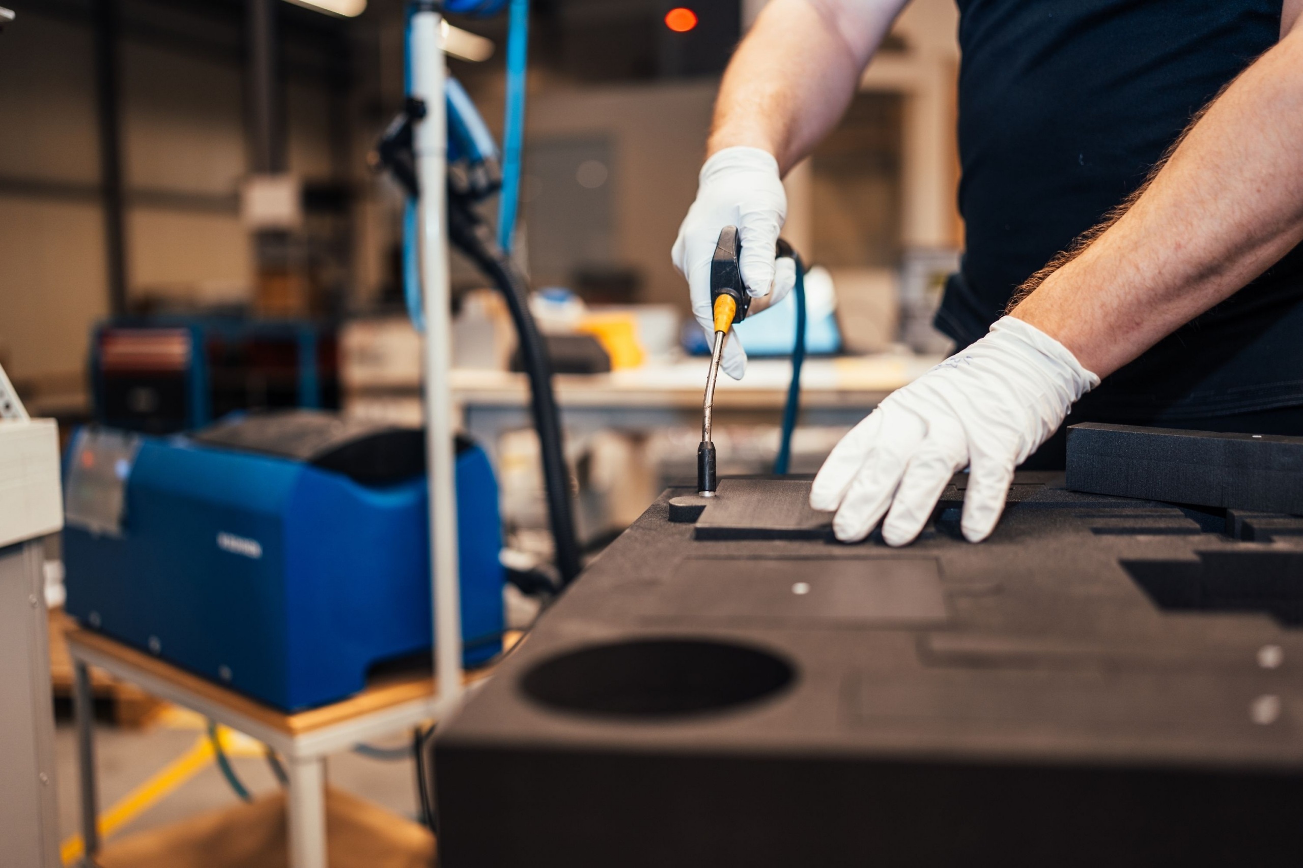 Medewerker van Faes bewerkt met handgereedschap een op maat gemaakte schuiminlay voor een militaire case, bedoeld om gevoelige apparatuur tijdens transport tegen schokken en beweging te beschermen.