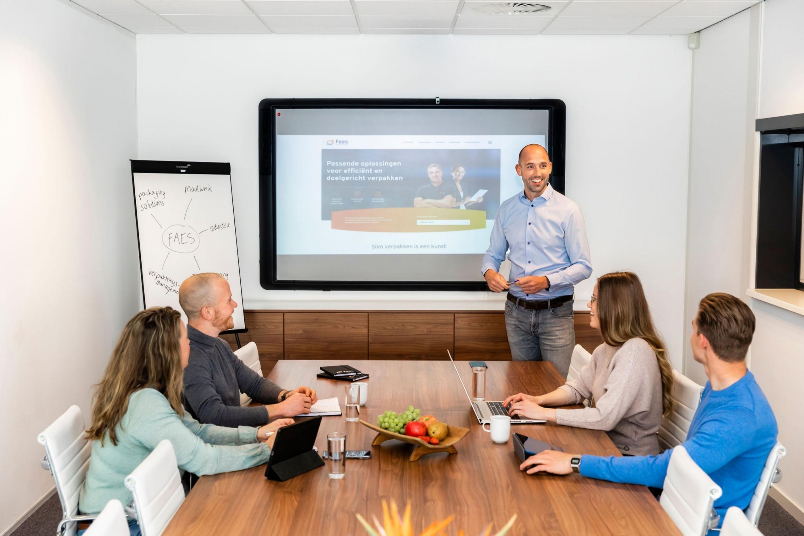 Een Faes-presentatie in een vergaderruimte met collega’s aan tafel, passend bij het helder toelichten van total cost of ownership-resultaten aan management.