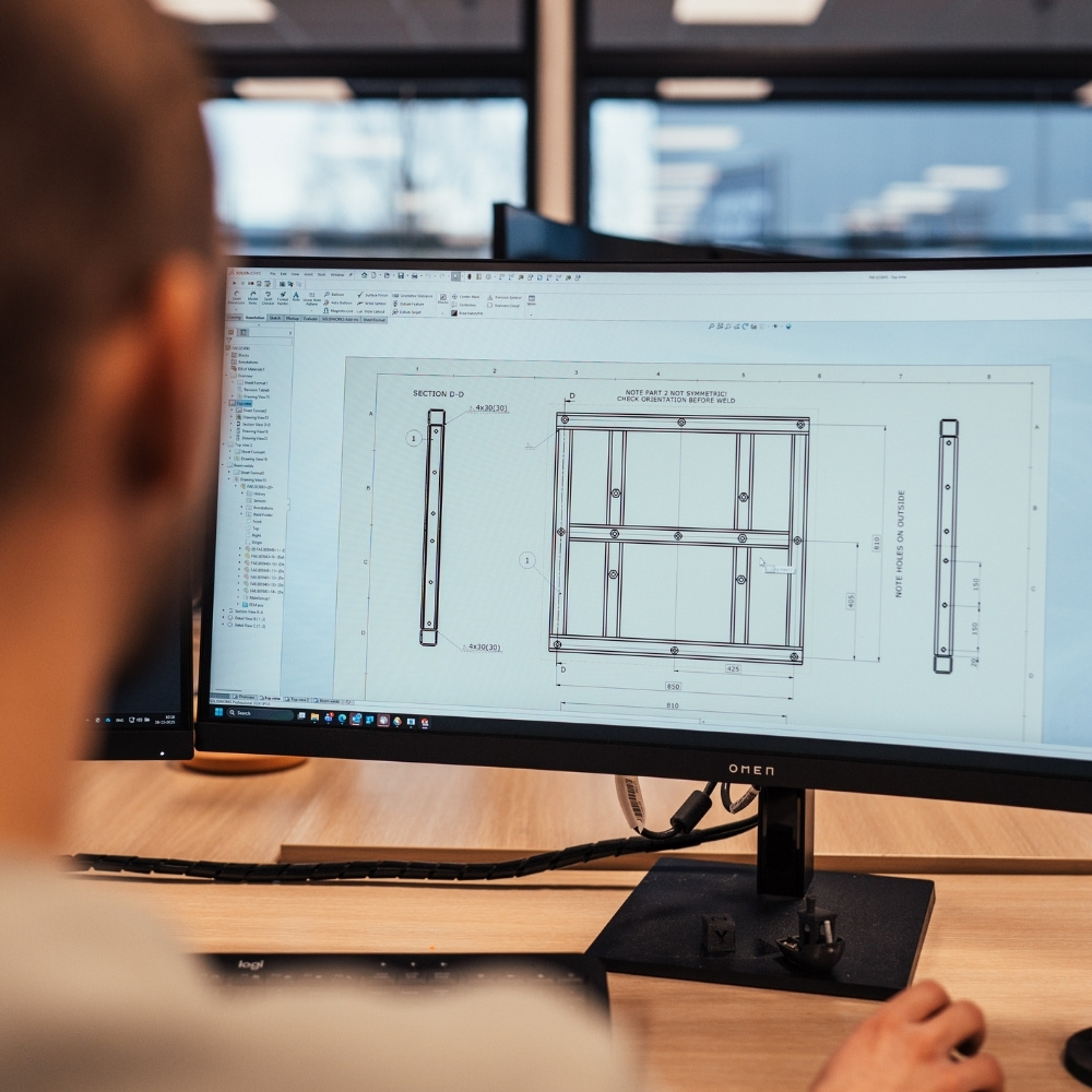 Engineer van Faes beoordeelt een technische CAD-tekening op het beeldscherm, passend bij het ontwerpen en valideren van verpakkingsoplossingen tegen elektromagnetische interferentie.