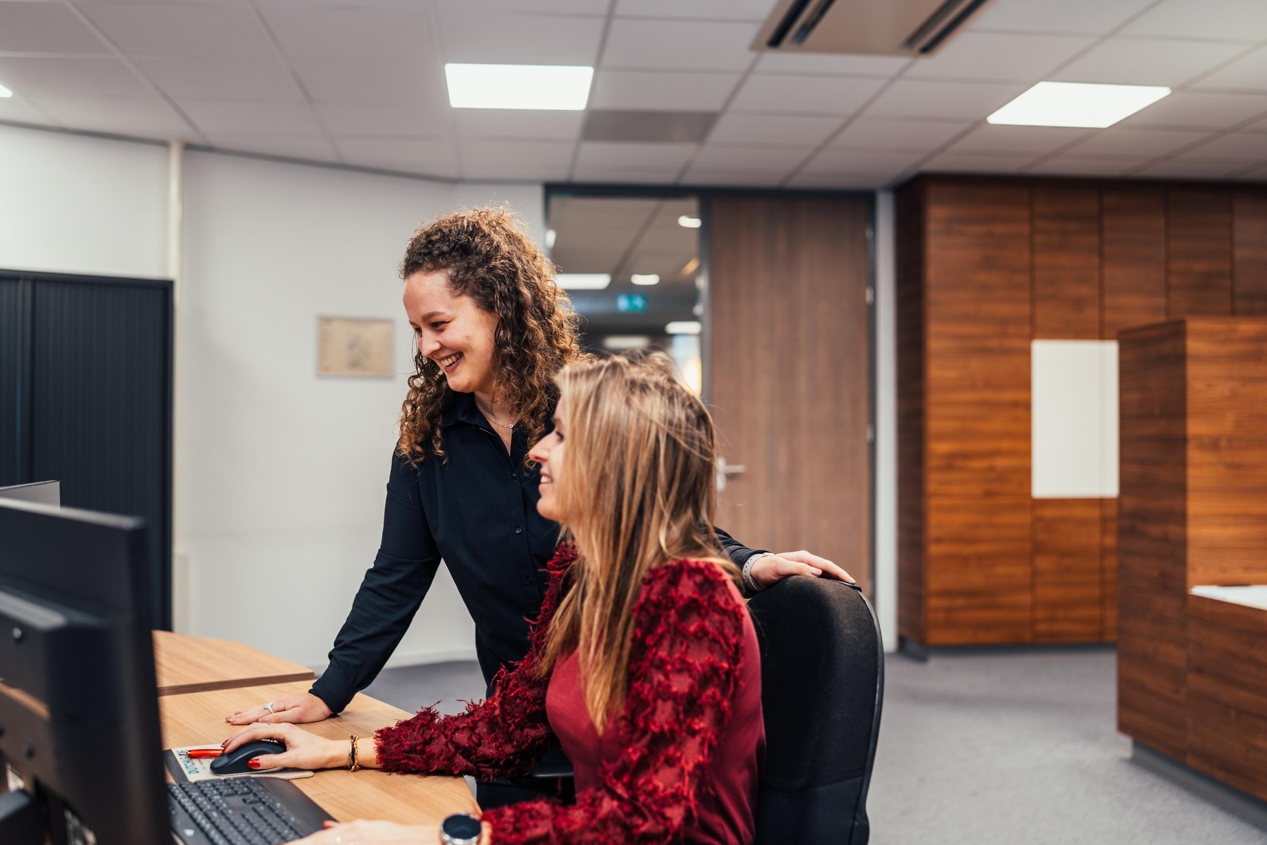 Faes-collega’s bespreken TCO-factoren en procurementkeuzes achter een computer in een moderne kantooromgeving.