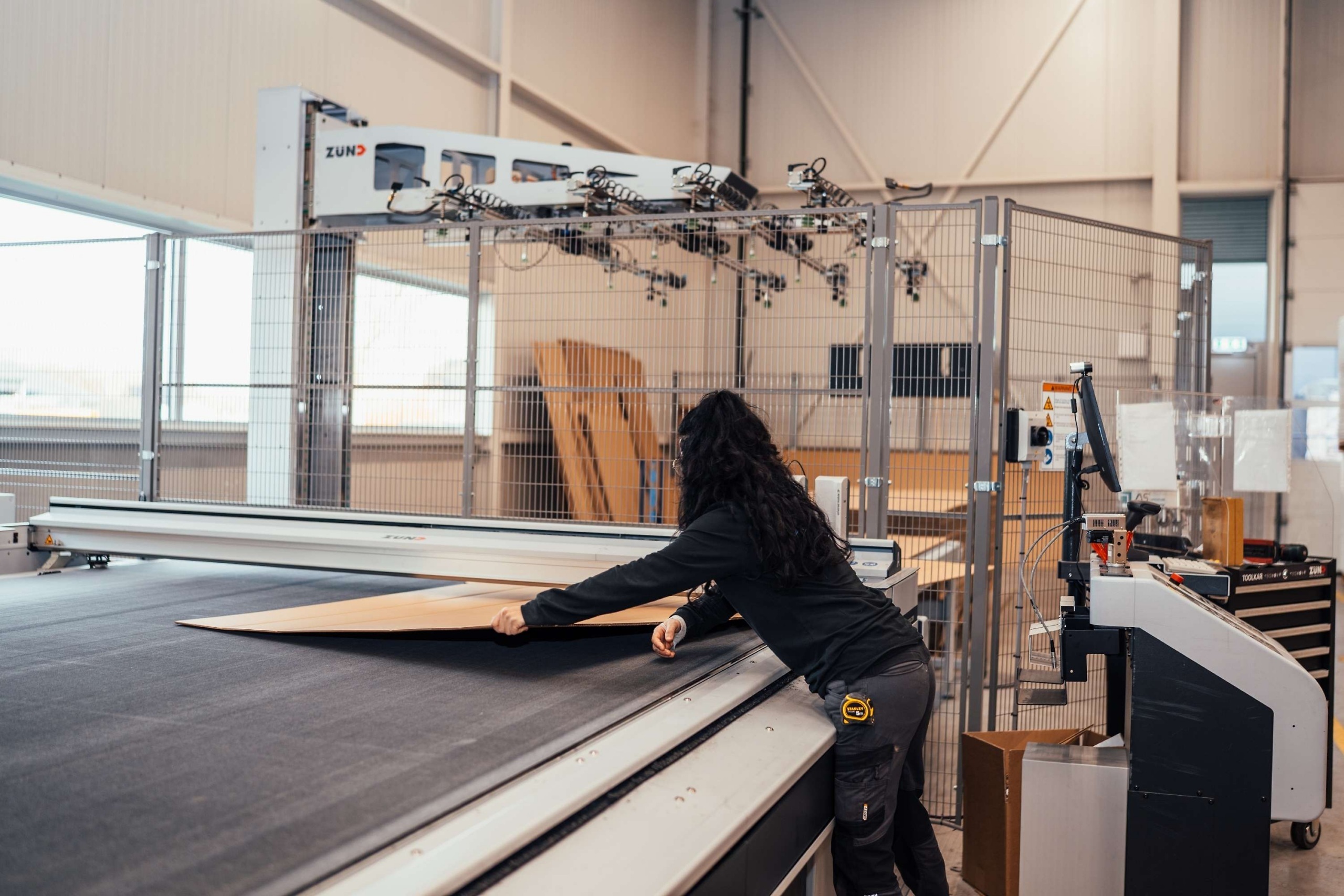 Medewerker van Faes legt verpakkingsmateriaal op een digitale snijtafel voor de productie van beschermende verpakkingen die transportschade aan medische goederen helpen beperken.