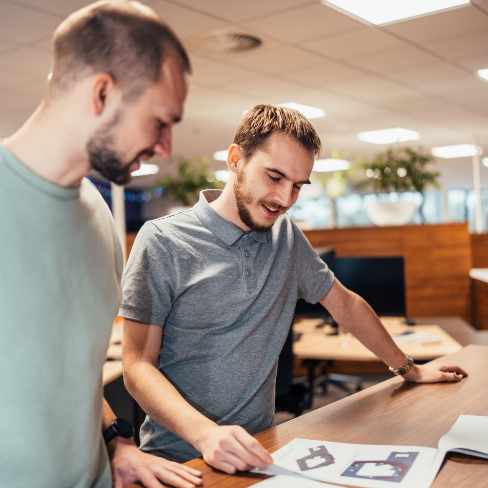 Twee medewerkers van Faes bespreken verpakkingsontwerpen en technische documenten aan een werktafel, passend bij zorgvuldige materiaalkeuzes en naleving van REACH-regelgeving.