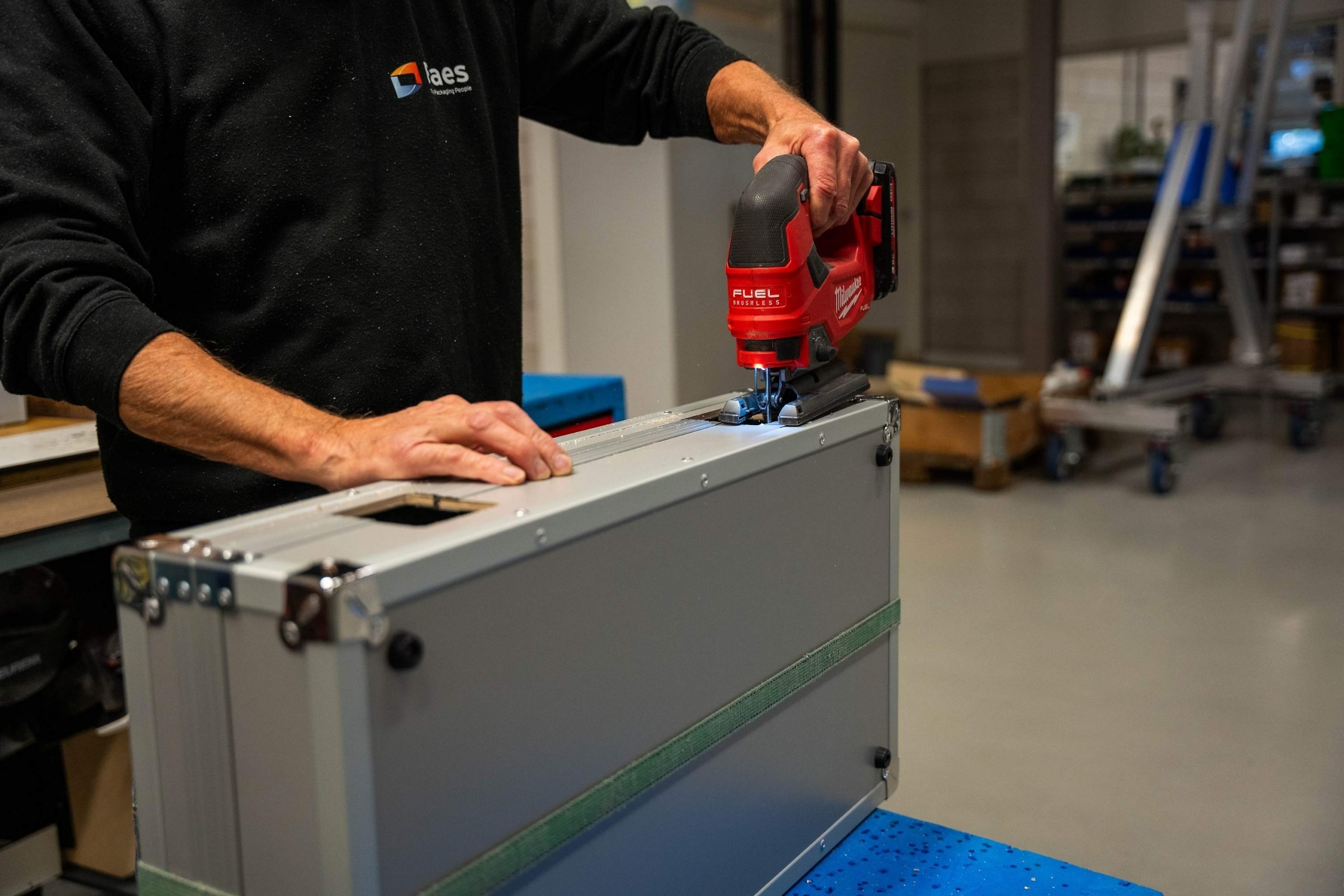 Medewerker van Faes bewerkt met een decoupeerzaag een grijze maatwerkcase in de werkplaats, passend bij herbruikbare industriële verpakkingen waarbij afwerking en levensduur meetellen in de TCO.